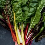 High angle close up of a bunch of freshly picked Swiss rainbow chard on grey background.